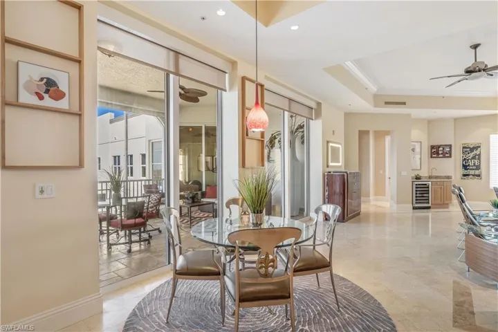 Dining space featuring ornamental molding, beverage cooler, ceiling fan, and a raised ceiling