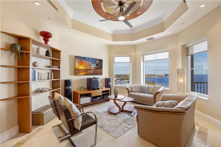 Living room featuring a tray ceiling, ceiling fan, and crown molding