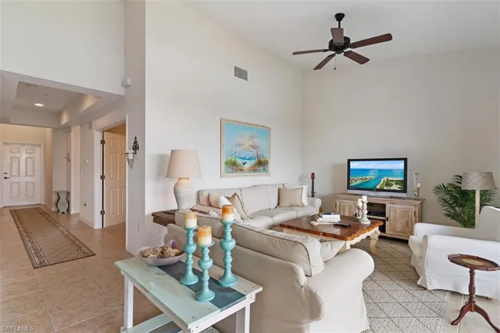 Spacious living area featuring high ceilings, a ceiling fan with integrated lighting, and tile flooring