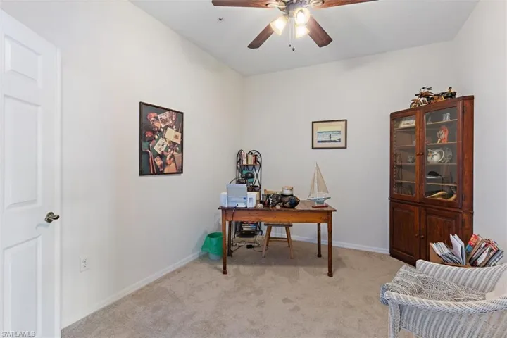 Room featuring a ceiling fan, light-toned carpeting, and a white paneled door