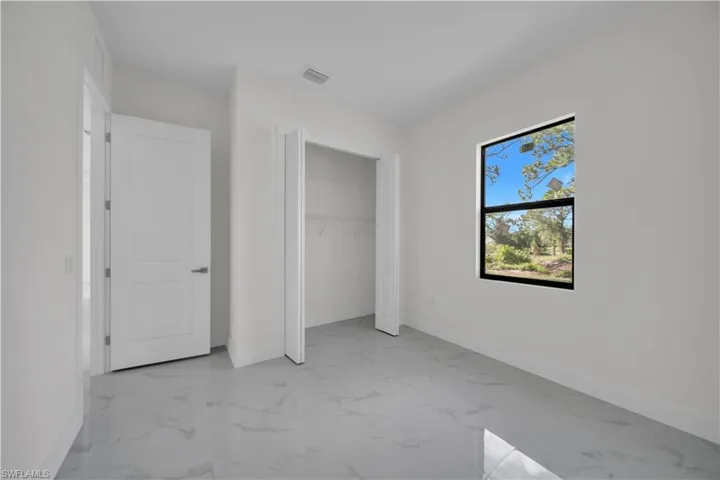 Unfurnished bedroom featuring marble finish floors and a closet