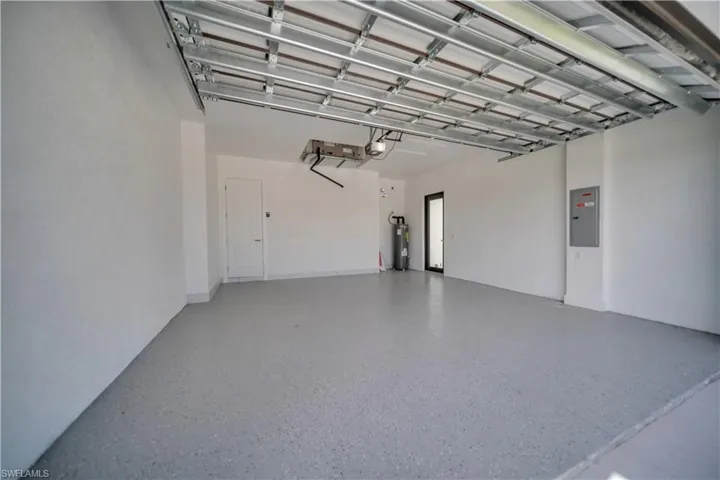 Garage featuring electric panel, water heater, and a garage door opener