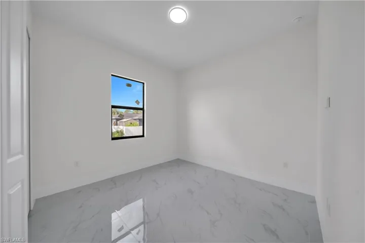 Spare room featuring marble finish floors and baseboards