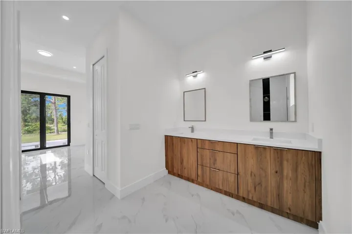 Full bath with double vanity, marble finish flooring, and recessed lighting