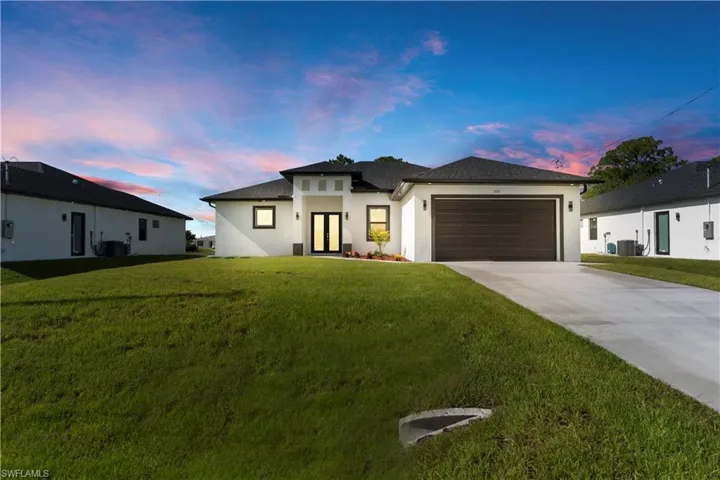 Prairie-style house featuring stucco siding, driveway, a garage, and a front yard