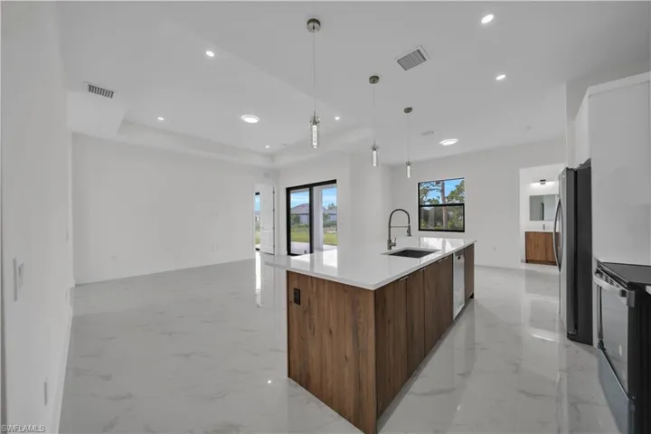 Kitchen with modern cabinets, stainless steel appliances, light marble finish flooring, a spacious island, and recessed lighting