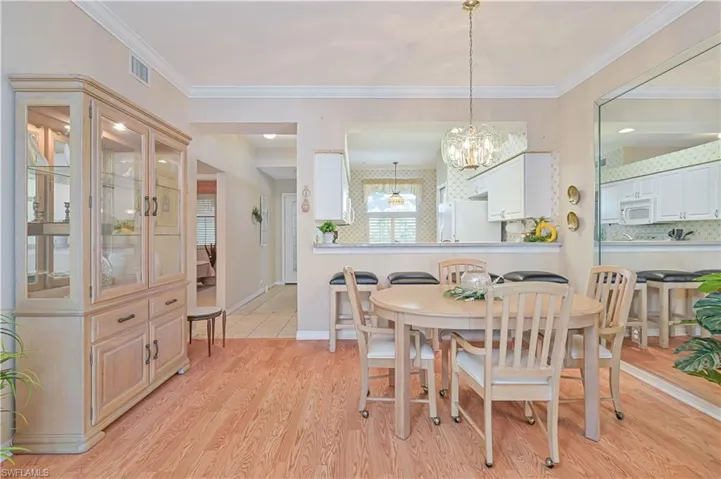 Dining room with a chandelier, light wood-style flooring, ornamental molding, and baseboards