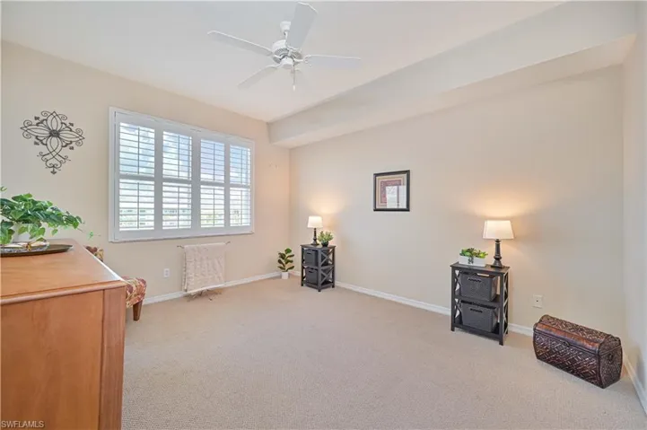 Living area with light colored carpet, baseboards, and ceiling fan