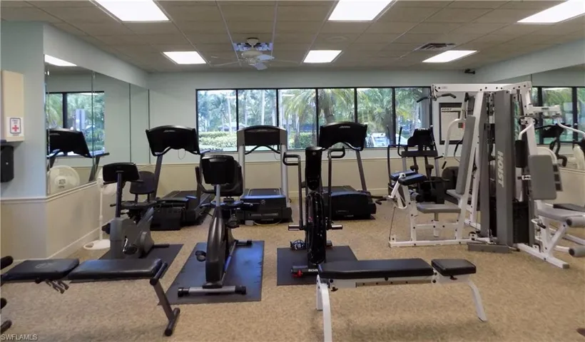 Workout area with a drop ceiling, carpet floors, and ceiling fan