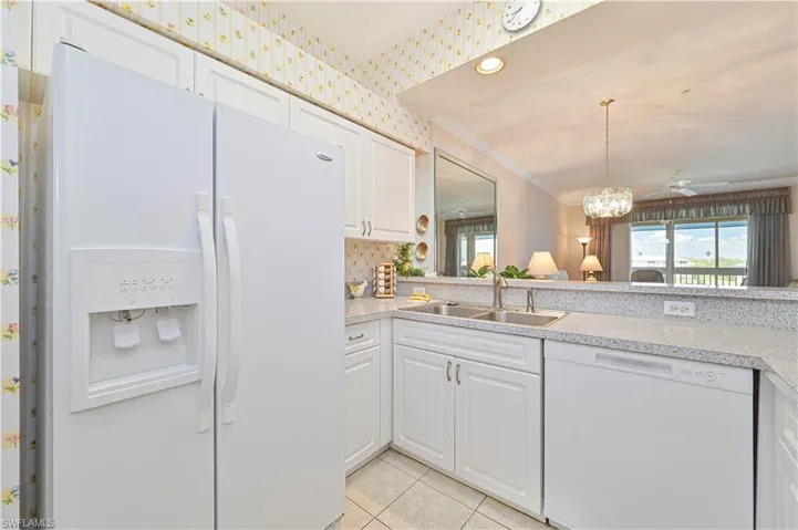 Kitchen featuring white appliances, a sink, light countertops, light tile patterned floors, and white cabinets