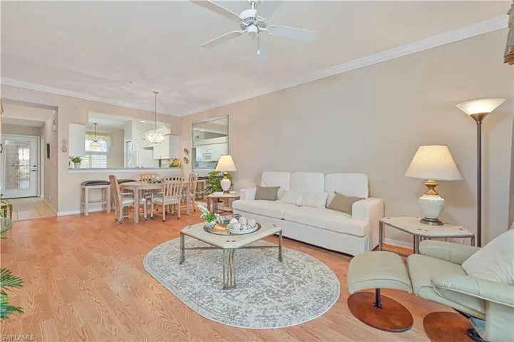 Living area with ceiling fan, a chandelier, light wood-style floors, ornamental molding, and baseboards
