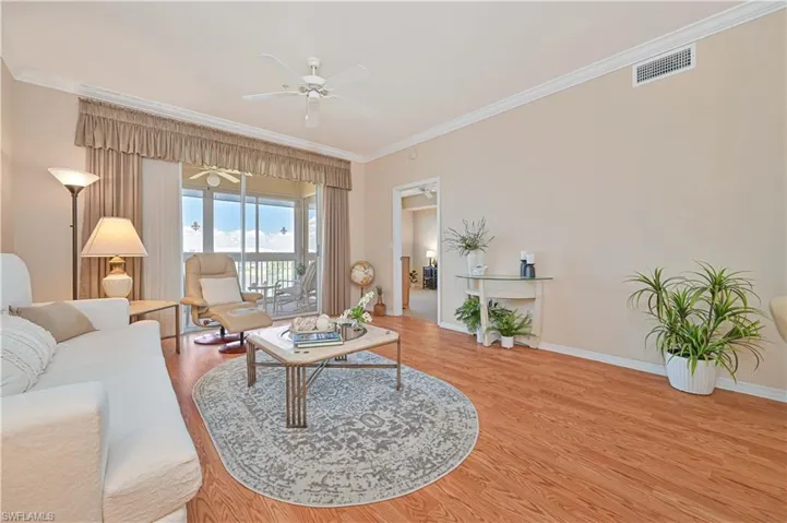 Living room featuring ceiling fan, crown molding, wood finished floors, and baseboards