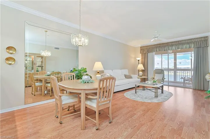 Dining area with wood finished floors, ornamental molding, a chandelier, ceiling fan, and baseboards