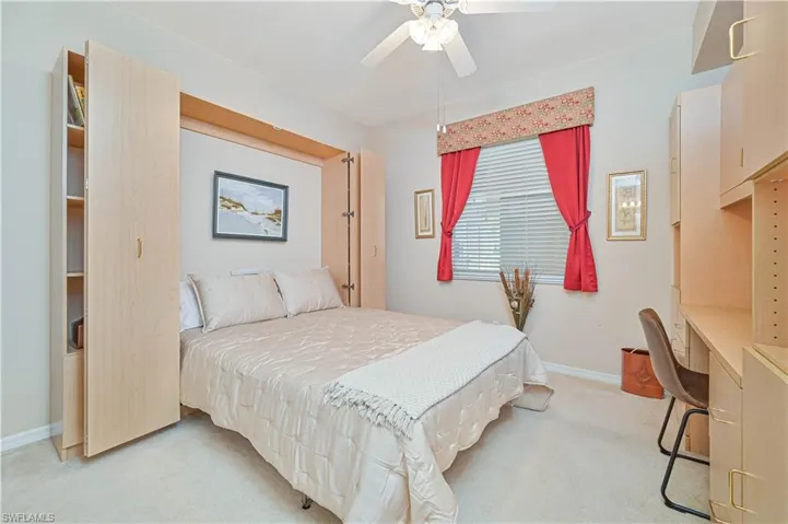 Bedroom with light carpet, an office area, baseboards, and ceiling fan