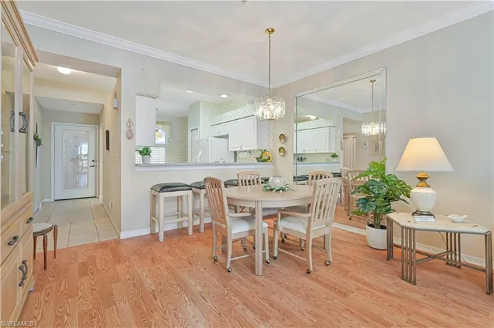 Dining area featuring baseboards, a chandelier, light wood-type flooring, and crown molding