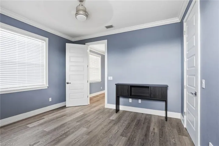 Unfurnished bedroom featuring crown molding, wood finished floors, and ceiling fan