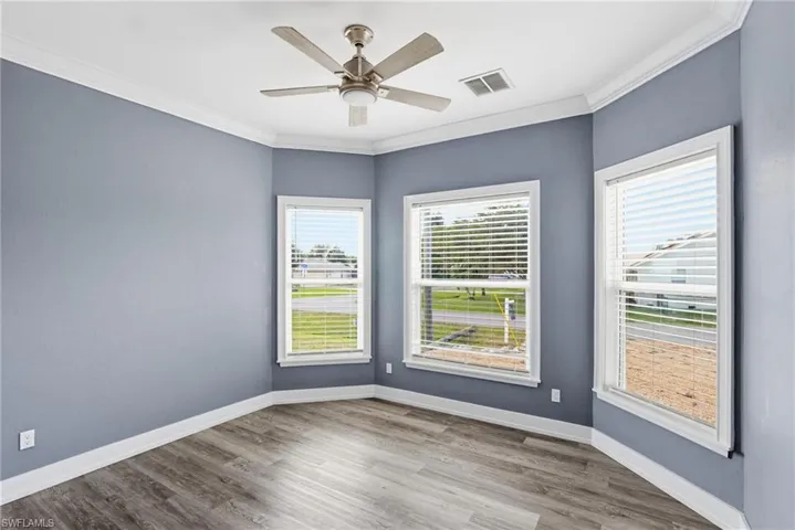 Spare room featuring ornamental molding, ceiling fan, and wood finished floors
