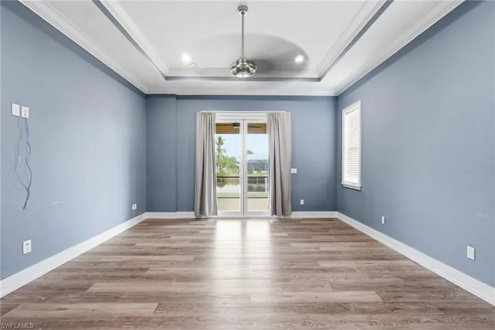 Empty room featuring light wood finished floors, crown molding, a ceiling fan, a raised ceiling, and recessed lighting