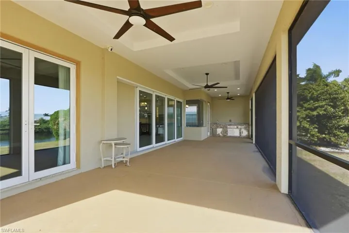 Unfurnished sunroom featuring a ceiling fan, a tray ceiling, and french doors