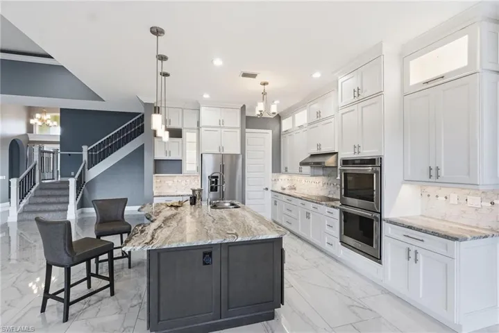 Kitchen with a chandelier, backsplash, white cabinetry, stainless steel appliances, and recessed lighting