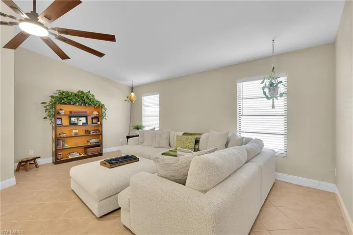 Living room featuring light tile patterned floors, a chandelier, and ceiling fan
