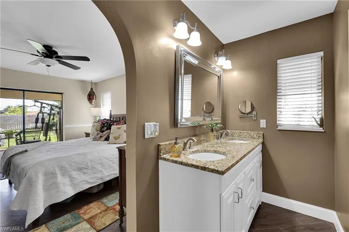 Ensuite bathroom with double vanity, dark wood finished floors, and ceiling fan