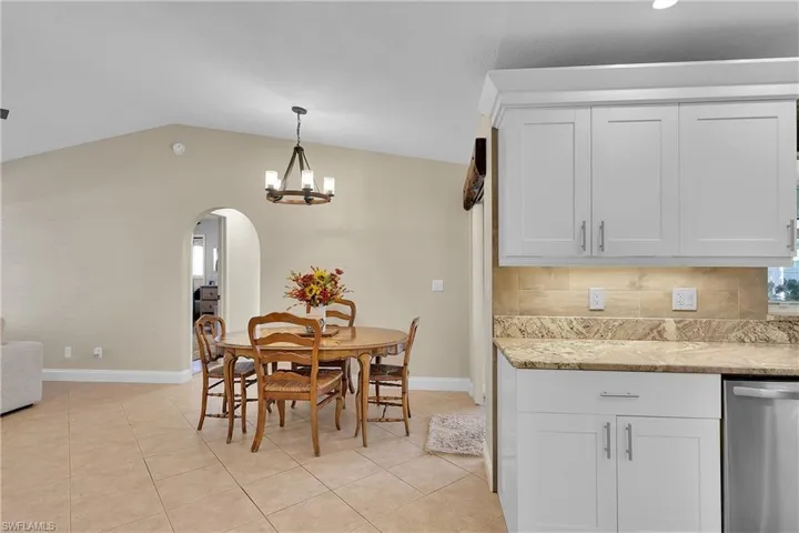 Dining room featuring ceiling fan, light tile patterned flooring, vaulted ceiling, a chandelier, and arched walkways