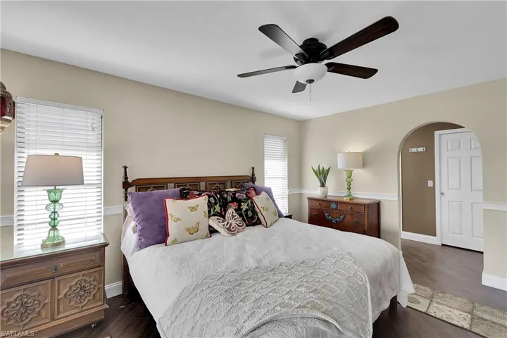 Bedroom with dark wood-style flooring, a ceiling fan, and arched walkways