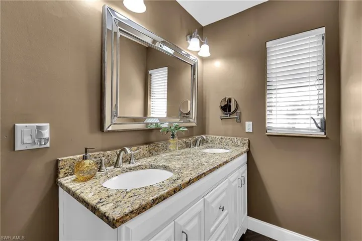 Full bathroom featuring double vanity and baseboards