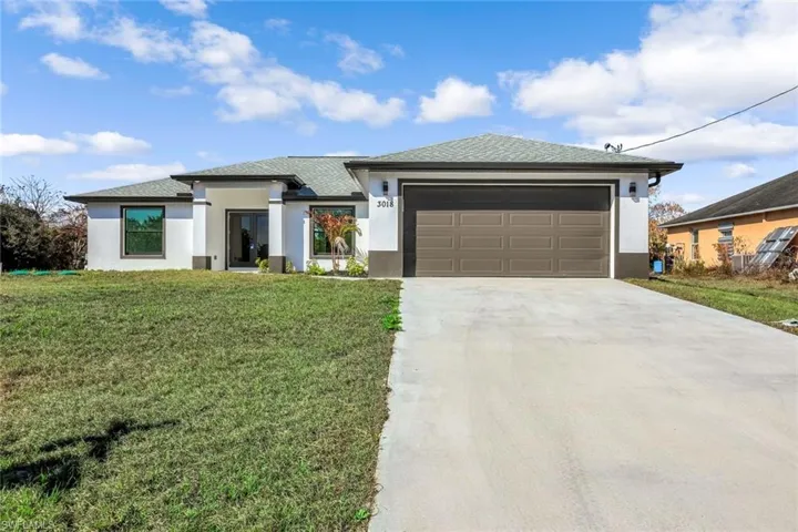 Clean, modern single-story exterior with a wide driveway, fresh landscaping, and a spacious front lawn.