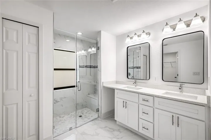Bright primary bathroom with double sinks, large mirrors, and clean modern finishes for shared convenience.