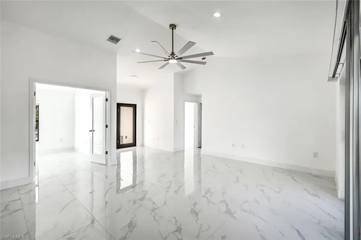 Bright, open living area with light tile flooring, a modern ceiling fan, recessed lighting, and a large window for natural light.