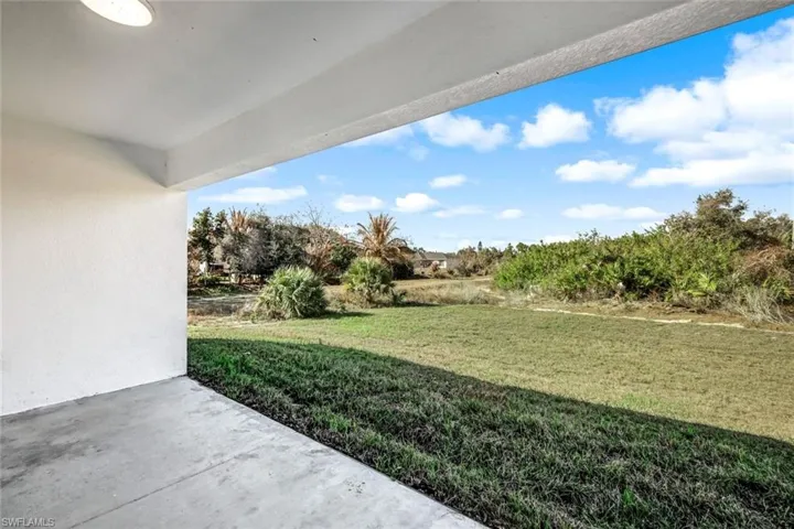Wide-angle covered lanai view showing the open yard and peaceful outdoor setting.