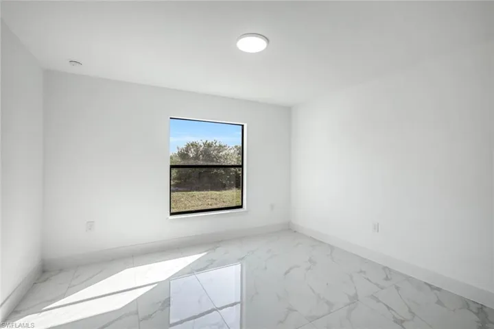 Bright room with recessed lighting and a window view—flexible for bedroom, office, or playroom.