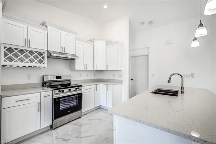 Stainless steel range and vent hood with sleek backsplash and bright cabinetry for a crisp, updated look.