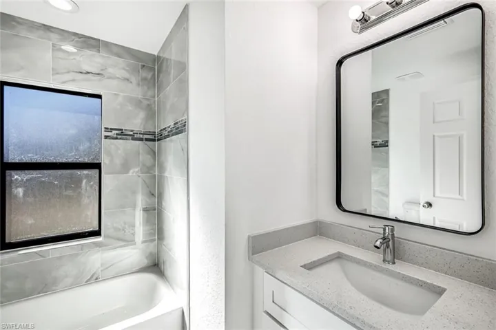 Close-up view showcasing modern tilework, sleek fixtures, and a clean vanity/mirror combination.