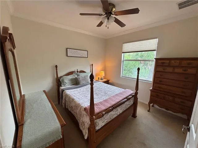 Carpeted bedroom featuring ornamental molding and ceiling fan