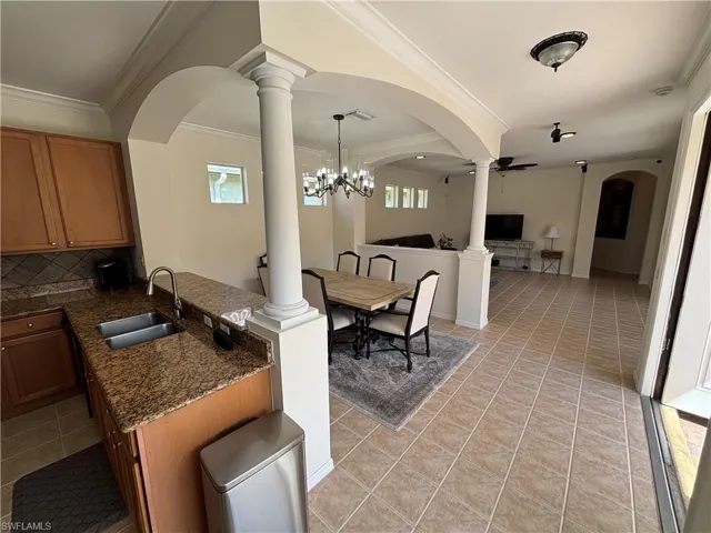 Kitchen with open floor plan, dark stone counters, wood finish cabinets, crown molding, and tasteful backsplash