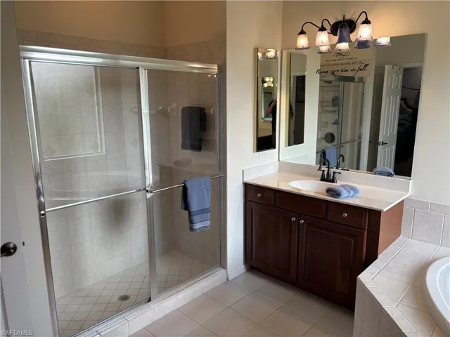 Full bathroom featuring vanity, a shower stall, light tile patterned floors, and a bath
