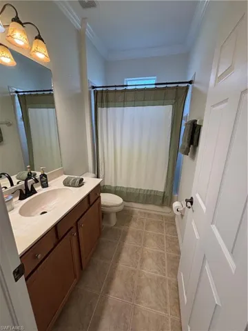 Bathroom featuring vanity, ornamental molding, shower / tub combo with curtain, and light tile patterned floors