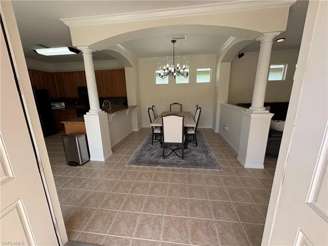 Dining area with crown molding, suspended lighting, and light tile patterned flooring
