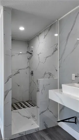 Full bath featuring vanity, a marble finish shower, and tile walls