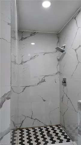 Full bath with a marble finish shower