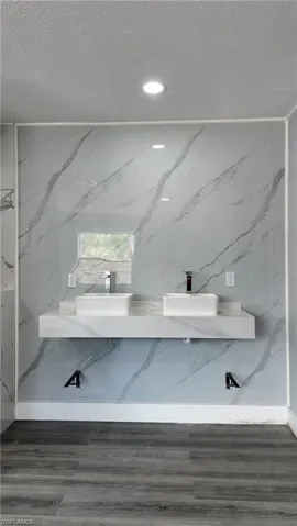 Bathroom featuring double vanity, a textured ceiling, and recessed lighting