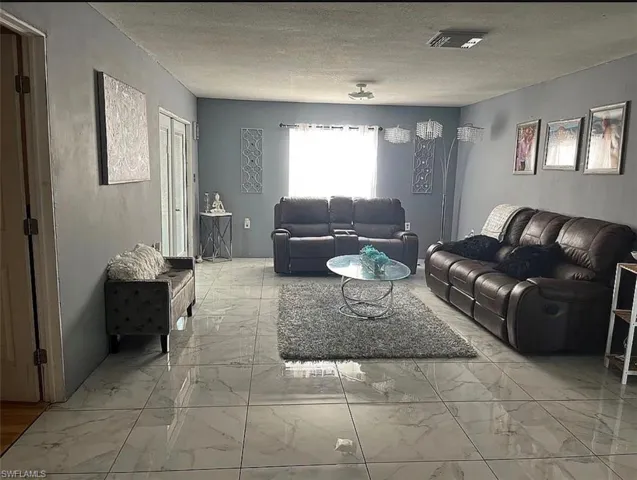Living room featuring a textured ceiling and light marble finish flooring