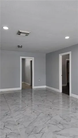 Empty room featuring recessed lighting, light marble finish flooring, and a textured ceiling