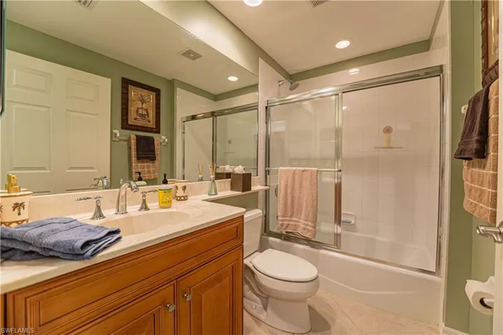 Bathroom with enclosed tub / shower combo, light tile patterned floors, vanity, and recessed lighting