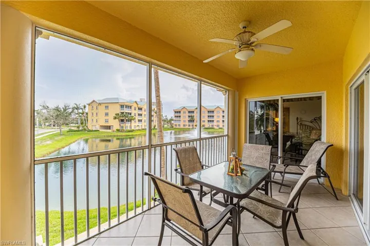 Sunroom / solarium featuring a ceiling fan, a water view, and a balcony