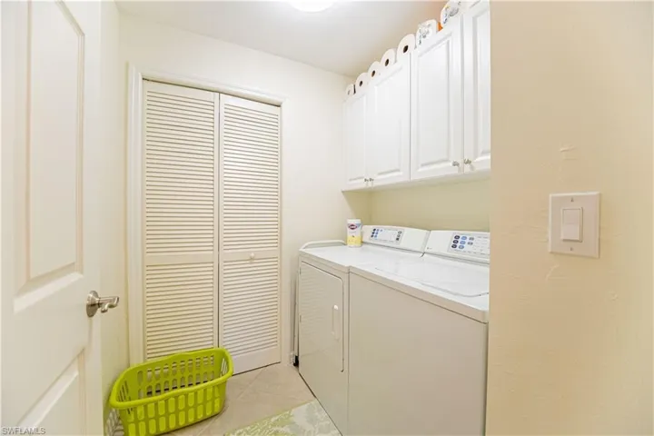 Laundry room featuring light tile patterned flooring, washer and dryer, and cabinet space