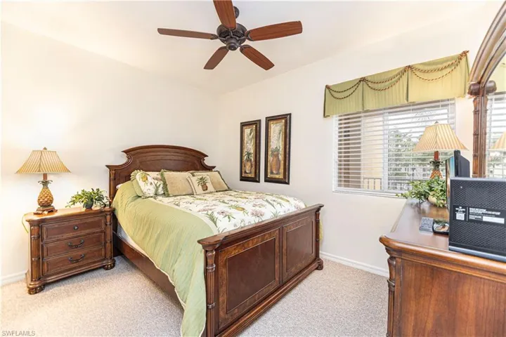 Bedroom with light colored carpet and a ceiling fan